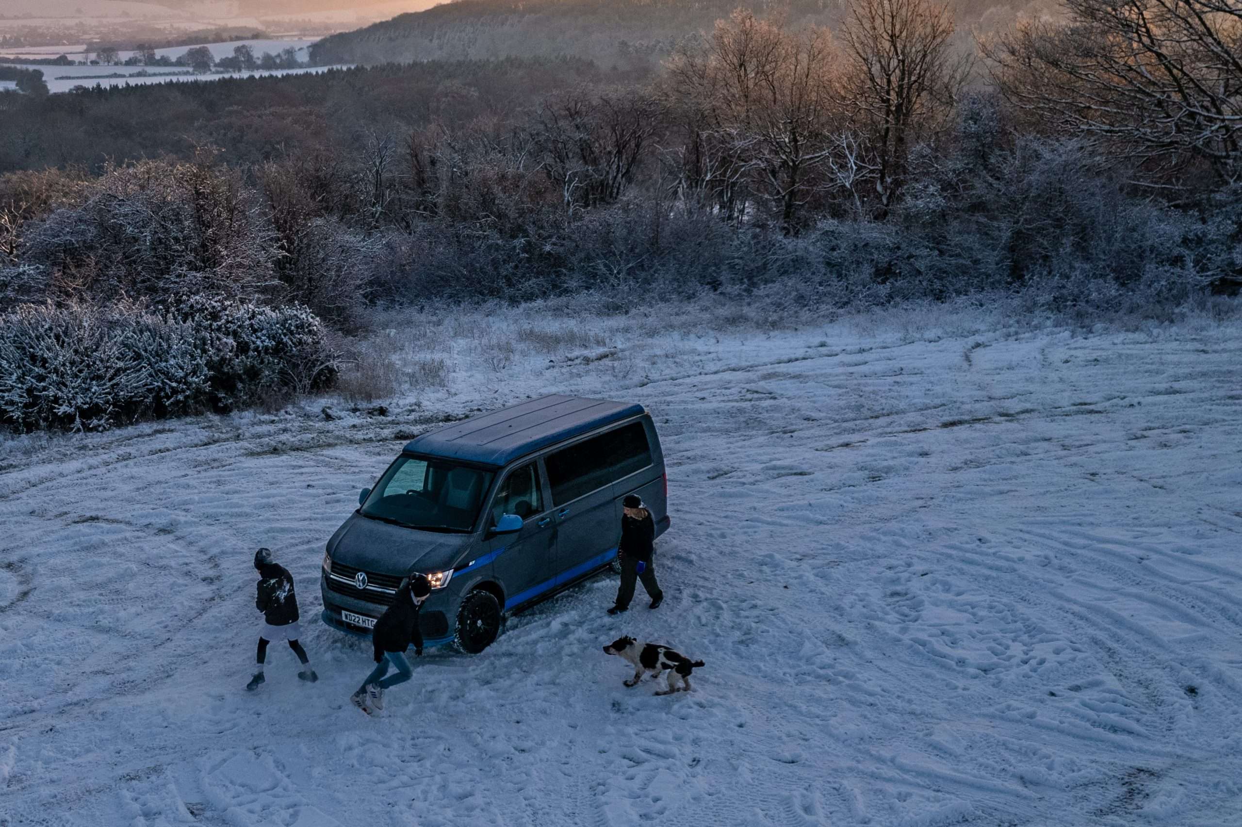 Children playing around a Volkswagen Campervan in the snow