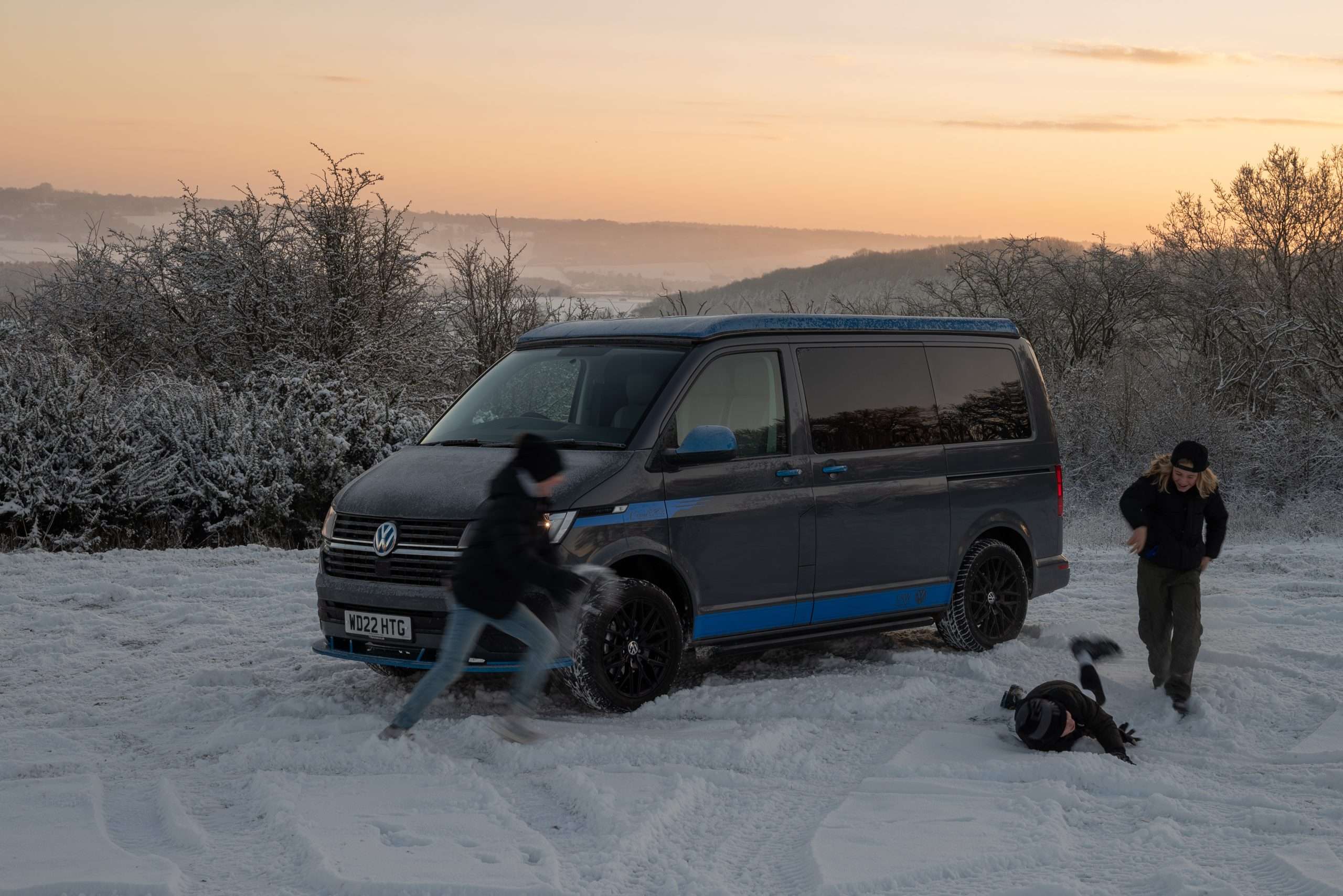 Children playing around a Volkswagen Campervan in the snow